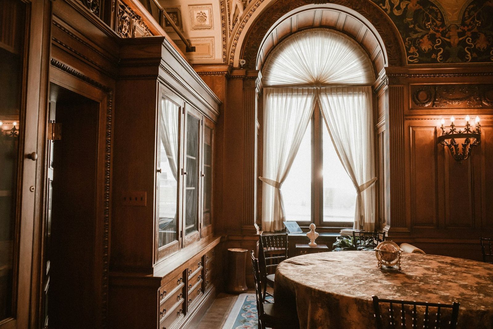 Salon d’appartement ancien avec grande fenêtre voûtée et voilages